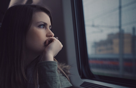 Woman sitting in the passenger seat of a car, looking deeply out the window. 